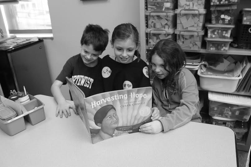 Bill Crouch, Alex Sarnoff, and Kiley Moss in Kathy Davidsons second grade class sit around the table and read Harvesting Hope, a book about Cesar Chavezs fight for the rights of migrant farmers.