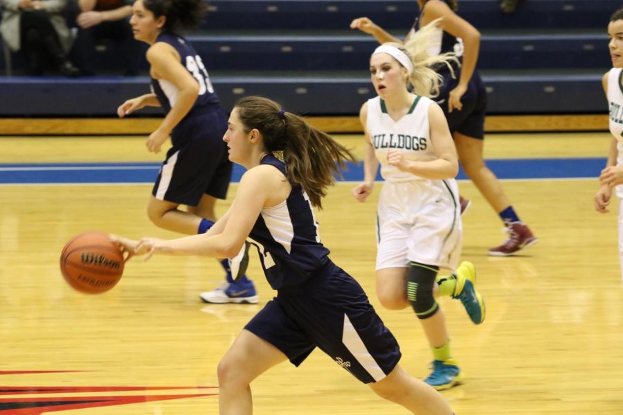 Molly Taylor dribbles down court in a basketball game.