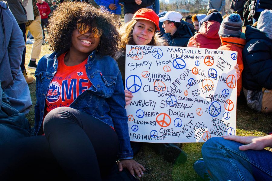 Seniors Morenike Fabiyi and Sidonia Ohringer get settled on the grass before the 17 minutes of
silence with their hand-made sign naming the sites of school shootings.