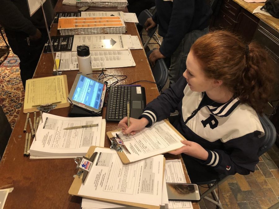 Junior Sarah-Jayne Austin, one of over 30 Parker students to serve as election judges, fills out registered voter certificates on Election Day while signing in voters.