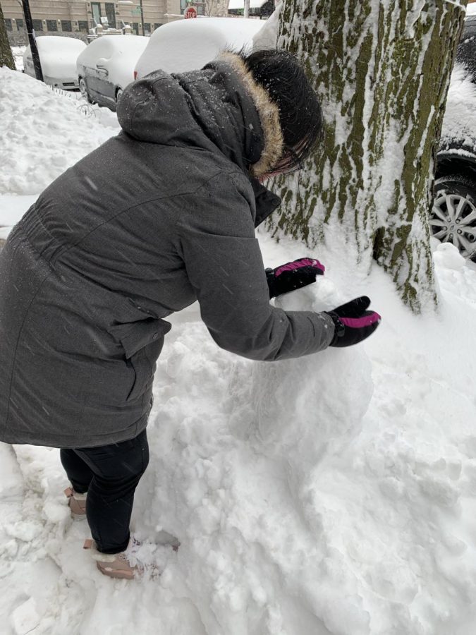 Junior Emma Manley shapes the beginning of a sidewalk snow friend.