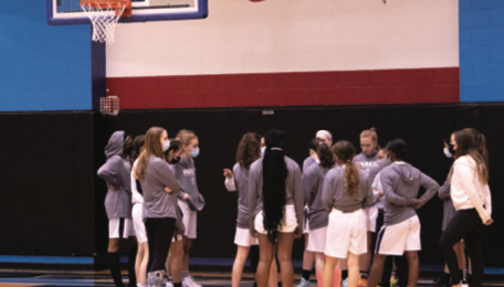 The Girls Basketball Team huddles together during their White Out Game 