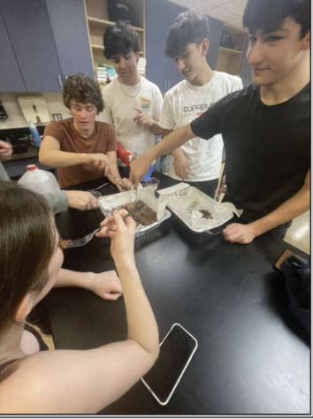 Baking Club members crowd around their brownies, which they love even more because they made them together.